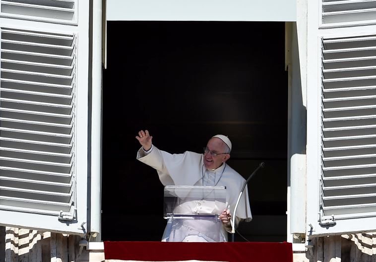 Pope Francis waves to pilgrims, gathered in St. Peter's square at Vatican, from the window of his appartment during his Sunday Angelus prayer on October 11, 2015.