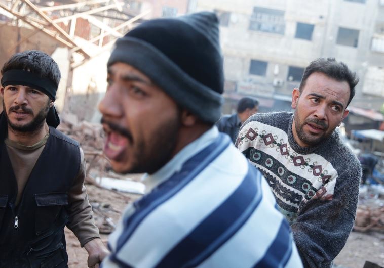 MEN CARRY casualties from a damaged site hit by missiles fired by Syrian government forces on a busy marketplace in the Douma neighborhood of Damascus, Syria on October 30.