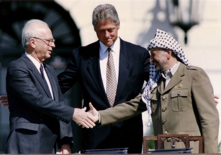 Then-PLO Chairman Yasser Arafat (R) shakes hands with then-prime minister Yitzhak Rabin (L), as U.S. President Bill Clinton stands between them