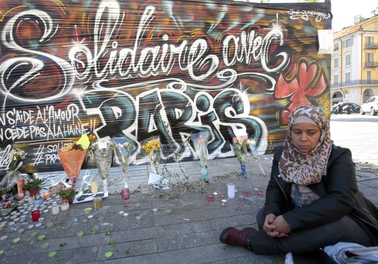 A woman sits by a poster which reads "Solidarity with Paris" in Nice, France, November 15, 2015, after a series of deadly shootings in Paris on Friday.