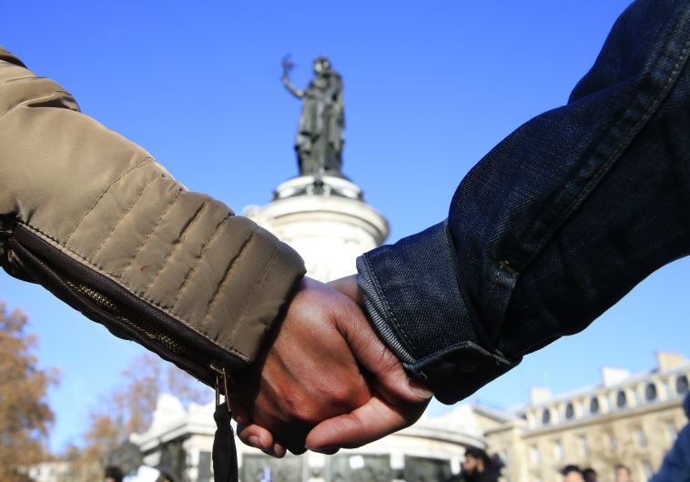 People hold hands to form a human solidarity chain at Place de la Republique near the site of the attack at the Bataclan concert hall in Paris, November 15, 2015. 