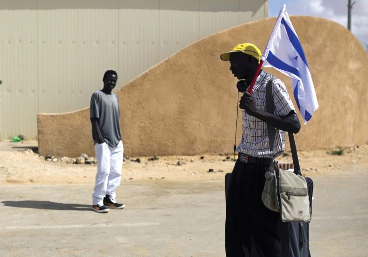 An African migrant holds an Israeli flag after being released from the Holot detention center in the Negev