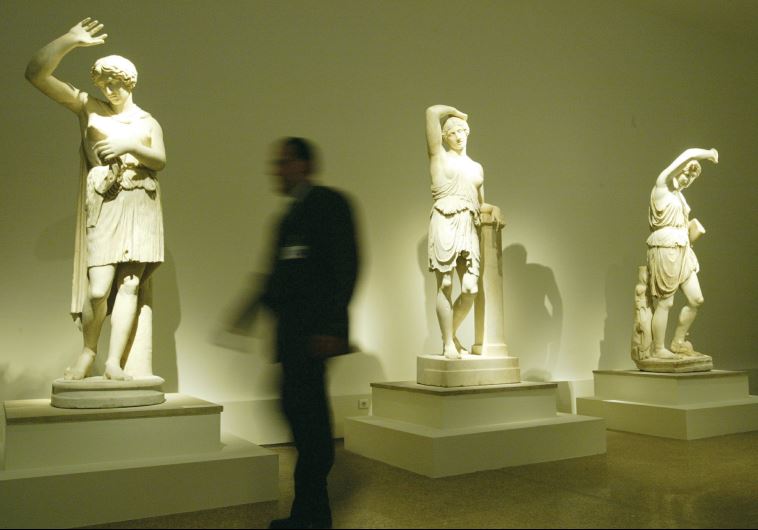 A guard walks past statues of wounded Amazones, made between 400 and 350 BCE, at the National Archeological Museum in Athens