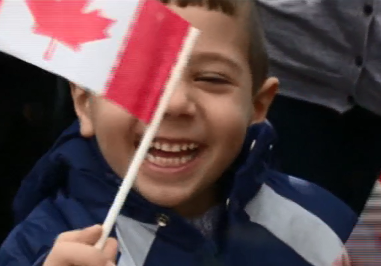 A Syrian refugee boy waves a Canadian flag as he settles into his new home in Canada, December 11, 2015.
