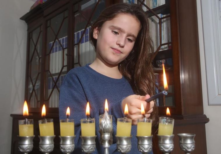 A young girl lights Hannuka candles 