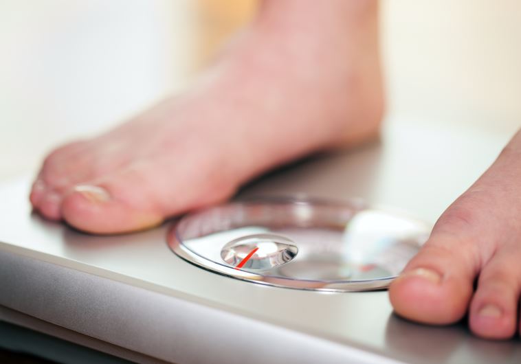 Woman standing on bathroom scale measuring her weight 