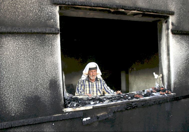 A man looks out of a house badly damaged by a firebomb attack by suspected Jewish extremists in the Palestinian village of Duma in the West Bank, July 31, 2015
