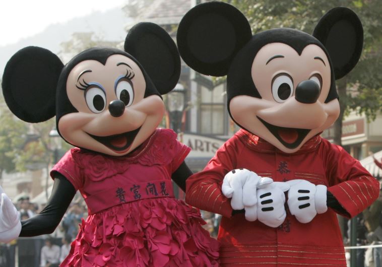People dressed as cartoon characters Mickey and Minnie greet visitors with their latest Year of the Mouse costumes at Hong Kong Disneyland