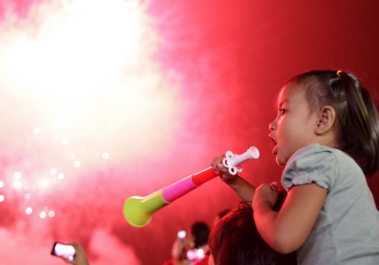 A girl blows a party horn at midnight during New Year celebrations in Manila, Philippines