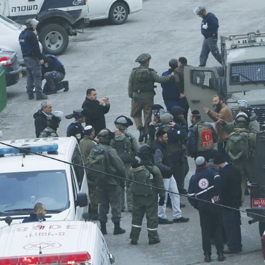 SECURITY PERSONNEL inspect the scene where a female soldier was shot yesterday in Hebron.