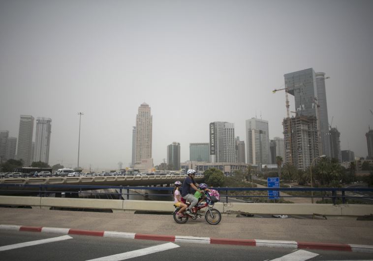 A man rides a bicycle during a sandstorm in Tel Aviv