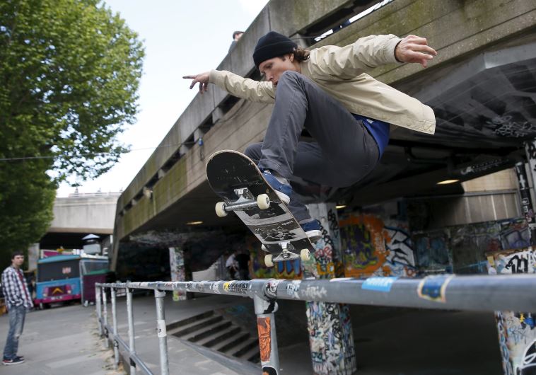 A skateboarder performs a jump over a railing