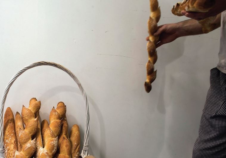 A MAN removes a baguette from a basket at a patisserie in Netanya. Many French Jews have expressed dismay over finding work in Israel and are immigrating elsewhere.