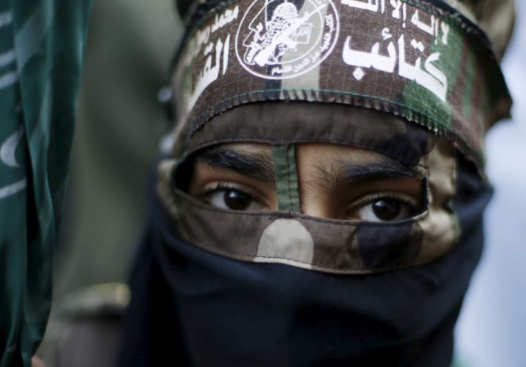 A masked Palestinian boy wearing the headband of Hamas's armed wing takes part in a rally marking the 28th anniversary of Hamas' founding in Gaza City