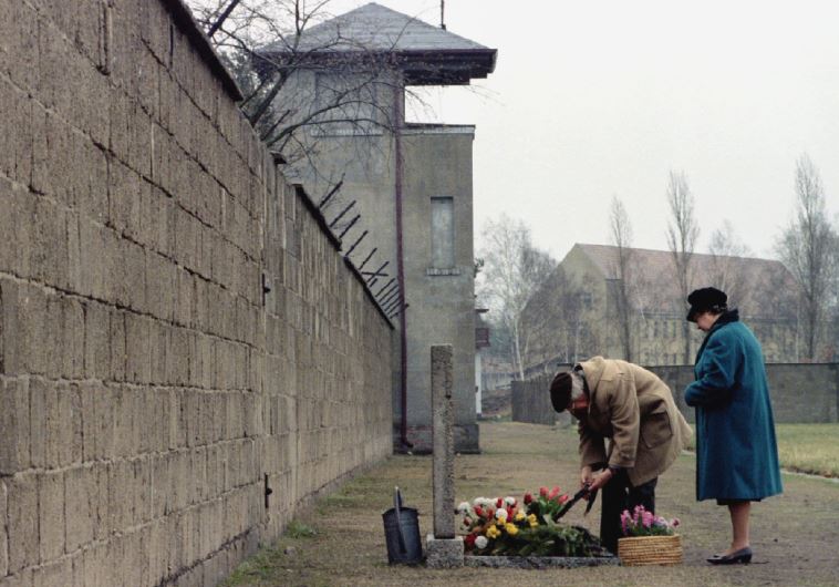 An elderly couple lays a wreath in front of a memorial for the victims of the Nazi concentration camp in Sachsenhausen