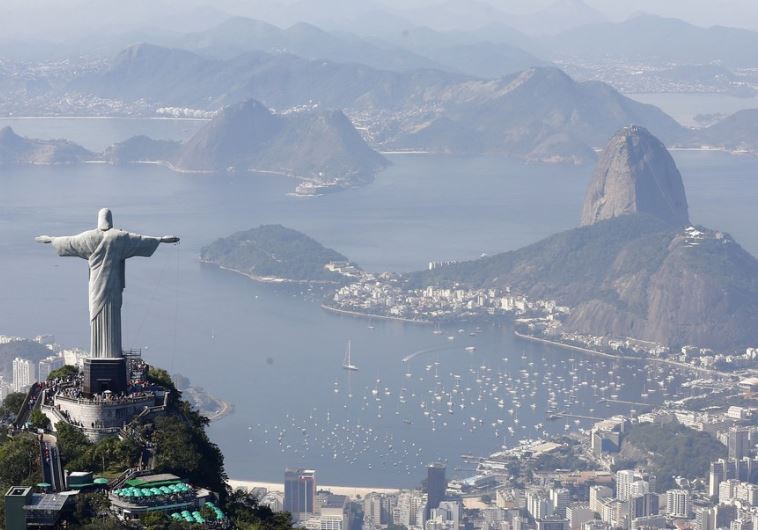 Tourists visit the Christ the Redeemer statue with Sugarloaf Mountain (R) in the distance in Rio de Janeiro