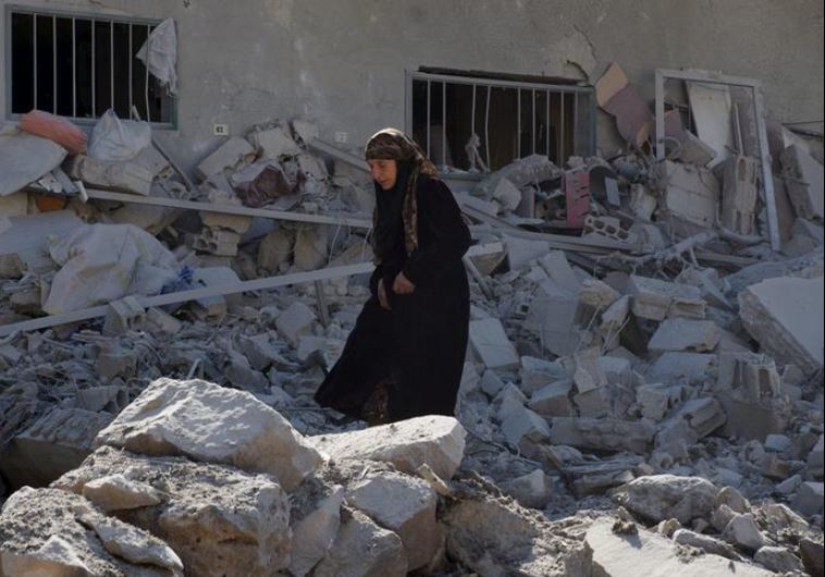 A woman makes her way through the rubble of damaged buildings after airstrikes by pro-Syrian government forces in the rebel held town of Dael, in Deraa Governorate, Syria February 12, 2016.