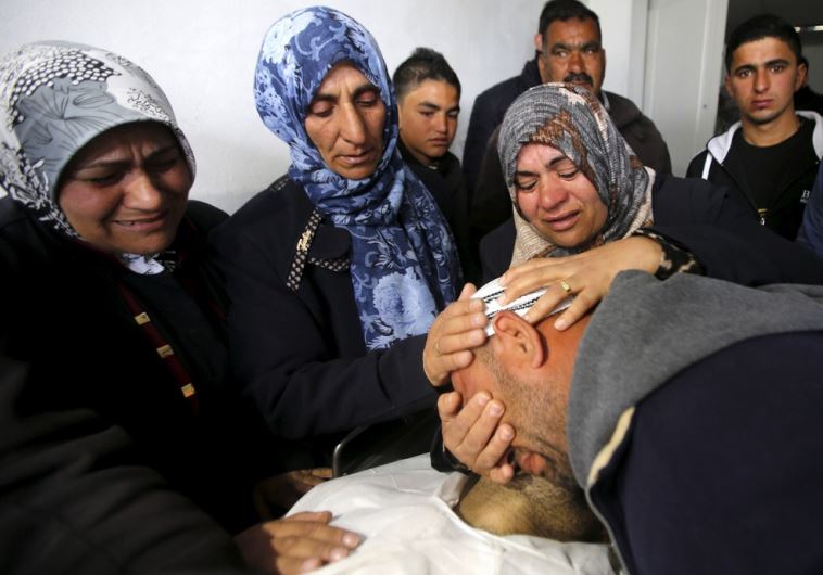 The brother and the mother (C) of Palestinian Qasim Jaber, 31, who the Israeli military said was shot dead by the Israeli army after he carried out an attack on Israelis, mourn as they look at his body in Hebron