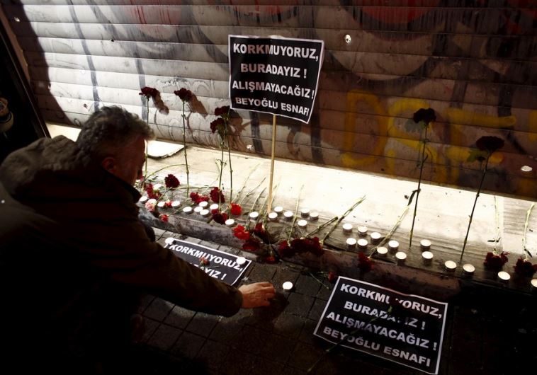 A man places carnations and a candle at the scene of a suicide bombing at Istiklal street, a major shopping and tourist district, in central Istanbul