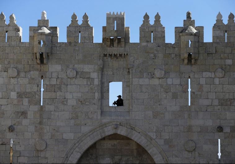 A Border Policeman holds his weapon as he guards the area from above while his comrades patrol at Damascus Gate in Jerusalem's Old City