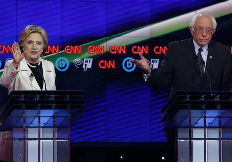 Democratic U.S. presidential candidate Hillary Clinton (L) speaks as Senator Bernie Sanders reacts during a Democratic debate hosted by CNN and New York One at the Brooklyn Navy Yard in New York April 14, 2016.