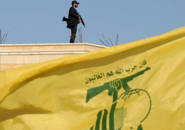 A Hezbollah member carries his weapon on top of a building in Bekaa Valley