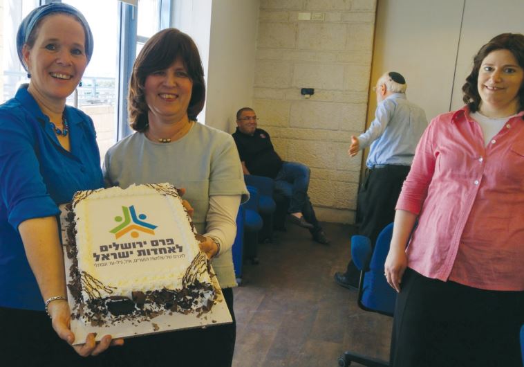 Rachelle Sprecher Fraenkel (left) and Tzila Schneider hold a cake celebrating the Jewish Unity Prize