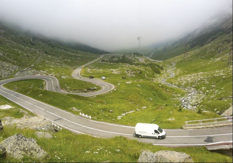 A van drives along the snaking road ascending the Fagaras Mountains