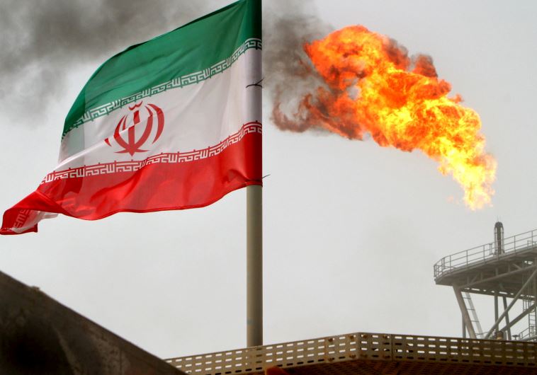 A gas flare on an oil production platform in the Soroush oil fields is seen alongside an Iranian flag in the Gulf 