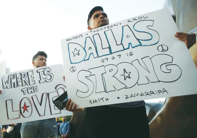 SUPPORTERS ATTEND a candlelight vigil at Dallas City Hall on Monday following the multiple police shootings in the city.