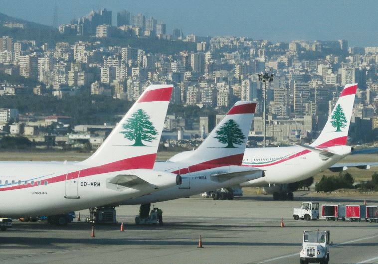 A luggage loading vehicle is driven past Middle East Airlines aircraft at Beirut Airport, Lebanon