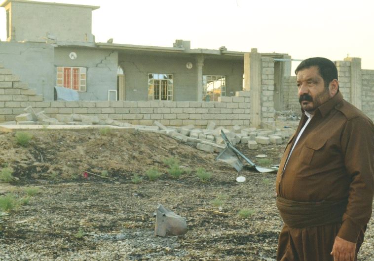 A KAKAI PESHMERGA volunteer stands next to a house destroyed by Islamic State. His brother was killed clearing explosives hidden by ISIS. (