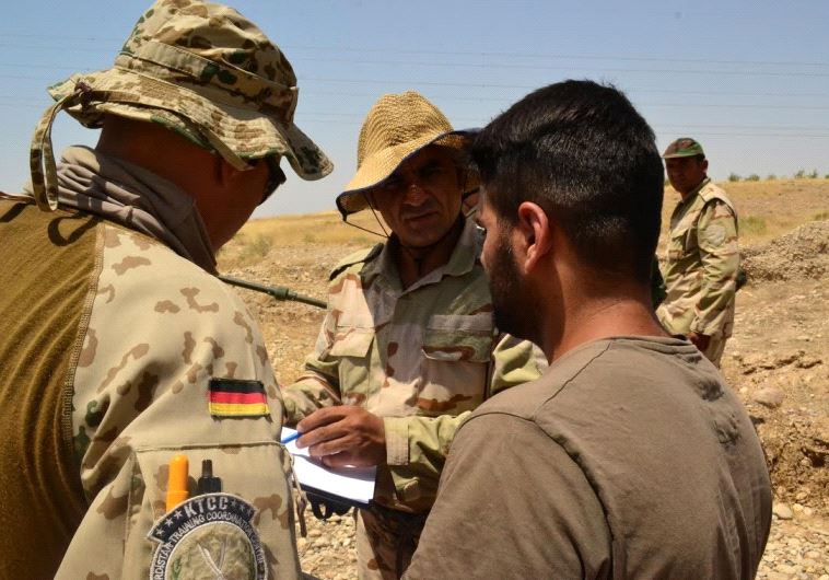 A German trainer with the Kurdistan Training Cooperation Center speaks with a translator and Peshmerga fighter about proper technique for counter-IED operations, in Bnsalwa, Iraq. 
