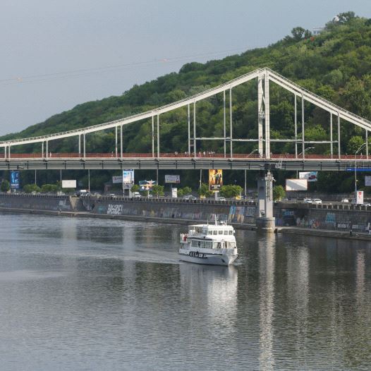 A MOTORBOAT passes under a footbridge over the Dnieper River in Kiev, Ukraine.