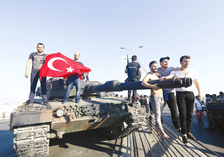 People pose near a tank after troops involved in the coup surrendered on the Bosporus Bridge in Istanbul on July 16