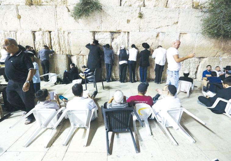 Worshippers sit on the ground on Tisha Be’av at the Western Wall, as a sign of mourning, in commemoration of the destruction of the Temple