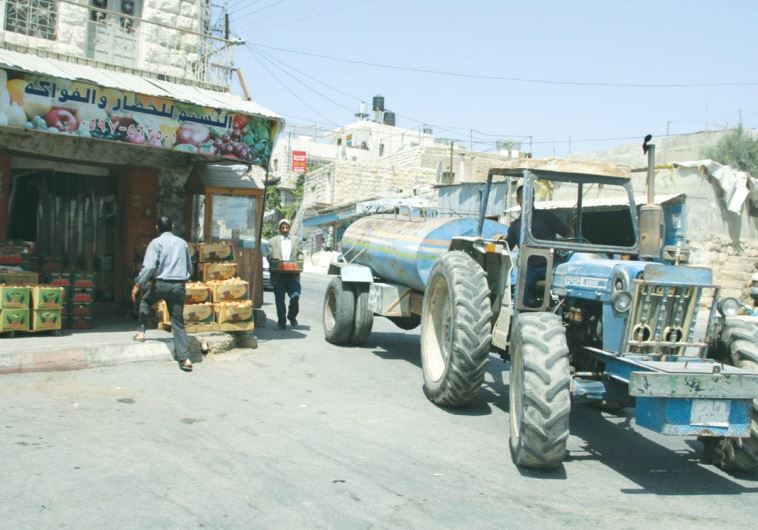 A TRACTOR carries water in the village of Sa’ir earlier this month.