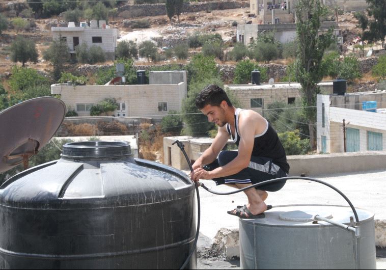 Man checking his water tank on a rooftop in Sa'ir