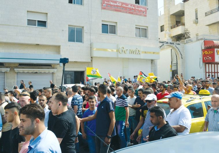 Protesters wave Fatah and Palestinian flags during a demonstration in Nablus in August 2016.