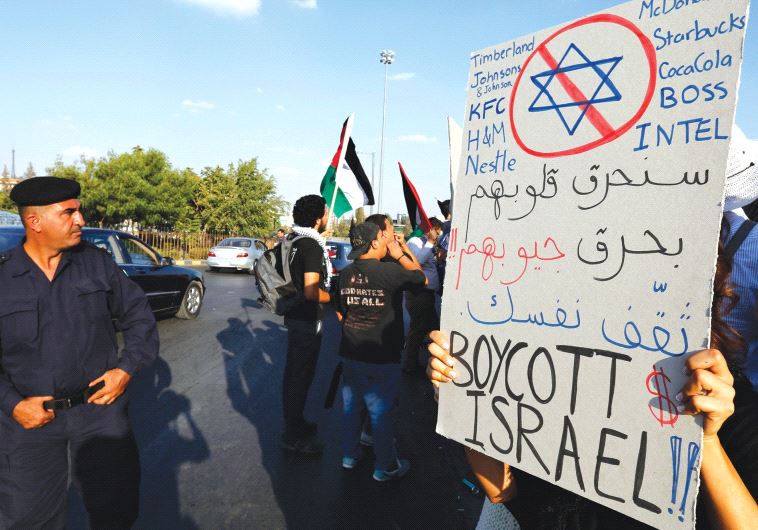 SAY NO to this. A Jordanian policeman stands guard near a protester holding a placard urging to boycott Israeli companies and products, in front of the Prime Minister’s office building in Amman.