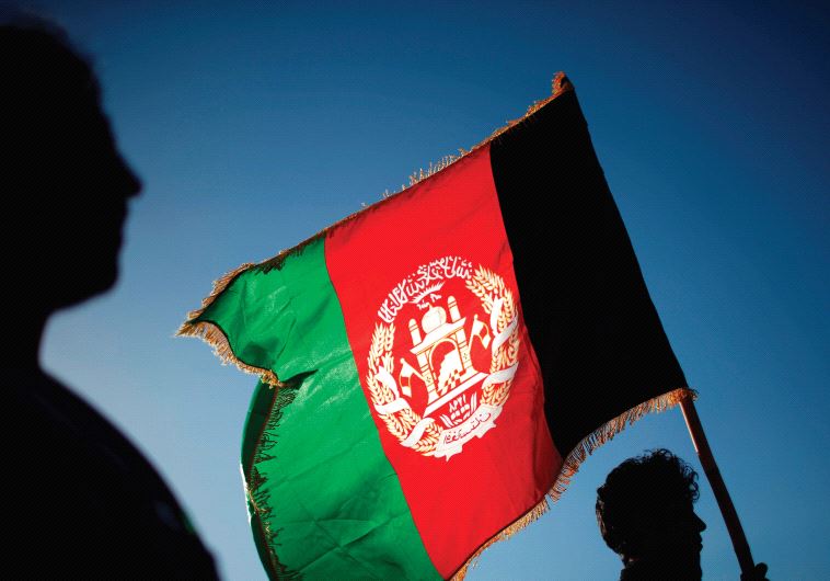 A MAN holds an Afghan flag, one of several that have the words ‘God is great’ on them