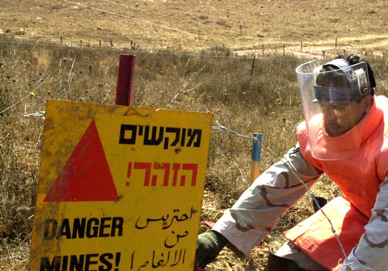 A soldier from the United Arab Emirate searches for unexploded land mines in southern Lebanon near Marajayoun August 13, 2003
