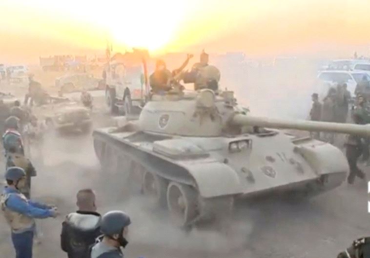 Tanks move past soldiers in military fatigues as the sun begins to set east of Mosul, where the Iraqi government launched a US-backed offensive to drive Islamic State from the northern city, in this still image taken from video released October 17, 2016