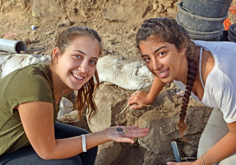 Dor Yogev and Ella Dicks hold coins discovered in the town of Kama