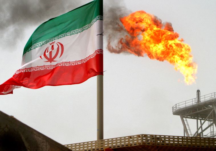 A gas flare on an oil production platform in the Soroush oil fields is seen alongside an Iranian flag in the Persian Gulf, Iran, July 25, 2005.