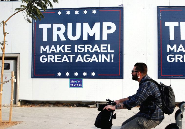 A man rides past a pro-Trump sign in Tel Aviv