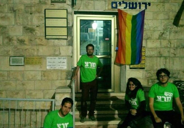 Meretz activists hoist the LGBT Pride flag outside the office of Chief Jerusalem Rabbi Shlomo Amar after he made disparaging remarks about the community