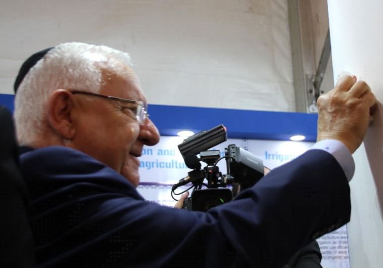 Israel President Reuven Rivlin places a Mezuzah at the Israeli exhibit booth at India premier agriculture fair. 