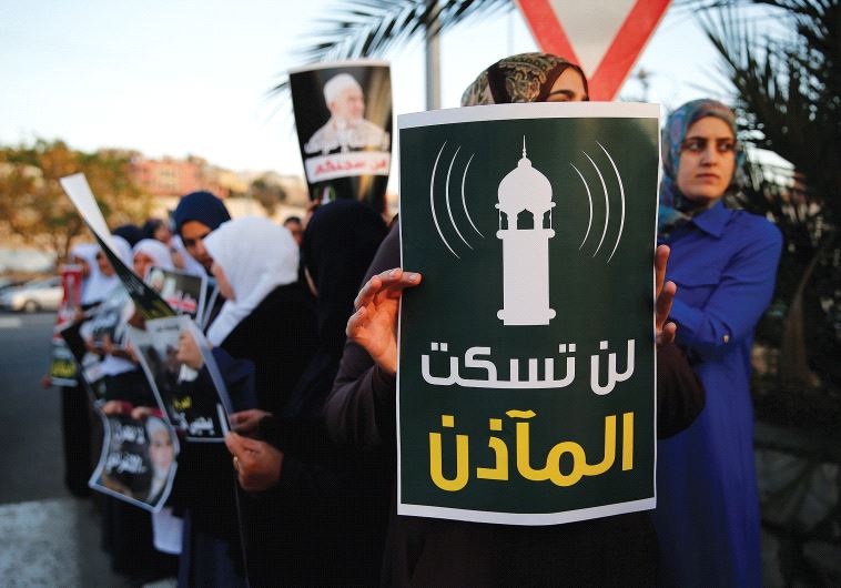 PROTESTERS AGAINST a law that would lower the volume of mosque loudspeakers hold a sign in Umm el-Fahm that reads, 'You will not silence the muezzin.'