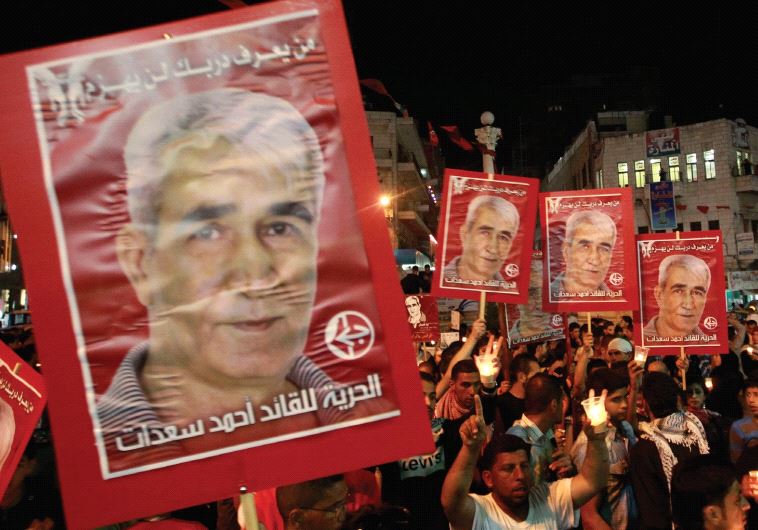 PALESTINIANS HOLD portraits of Ahmed Saadat, leader of the Popular Front for the Liberation of Palestine (PFLP), in Ramallah in 2012